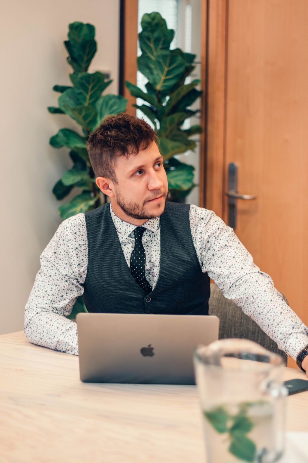 Marcel sitzt am Laptop und blickt nachdenklich zur Seite